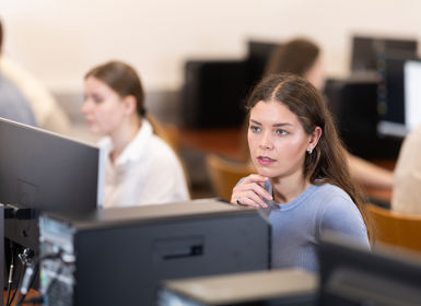 Photographie d'élèves devant des ordinateurs dans une salle de cours en faculté